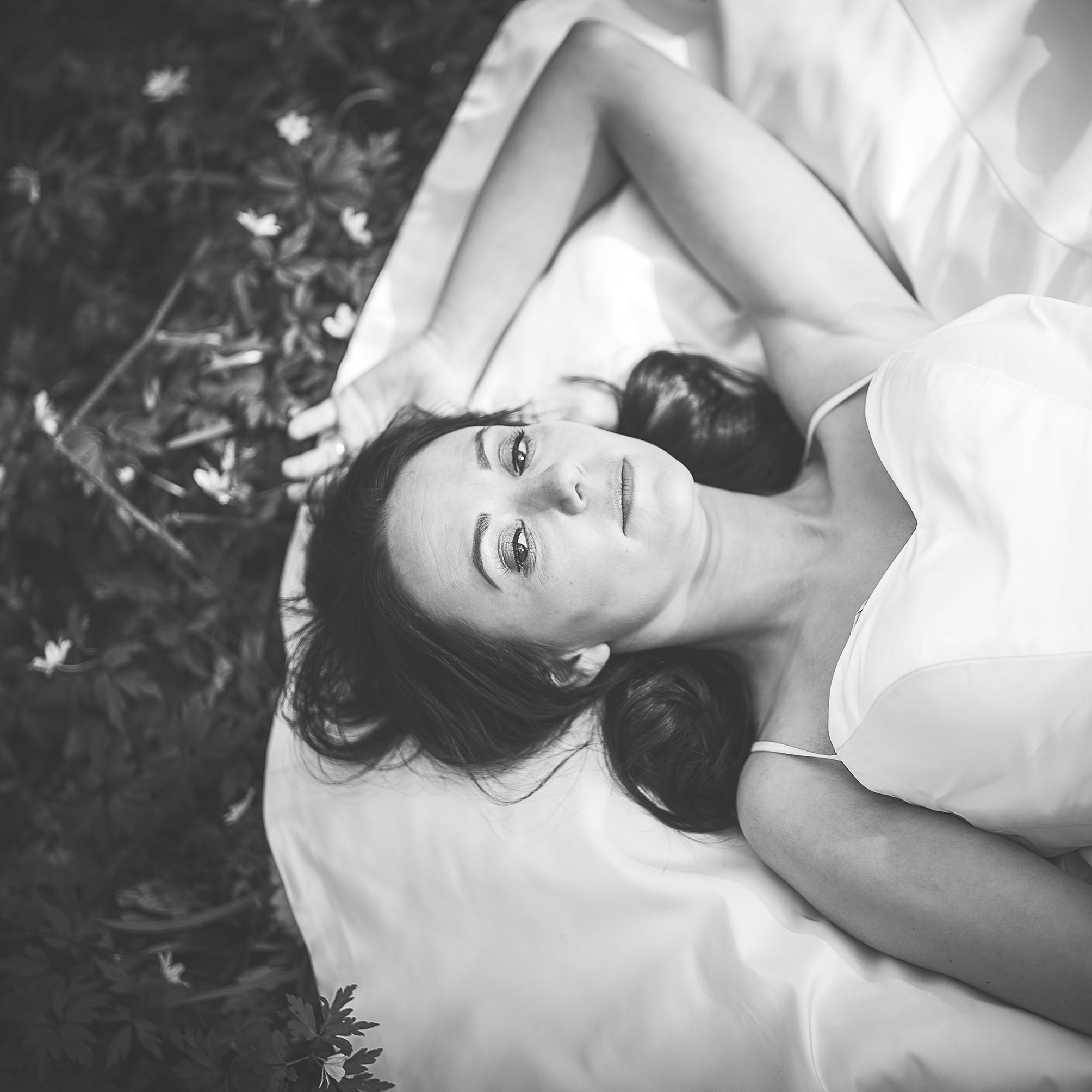 Bride laying amongst the woodland flowers at the Dreys