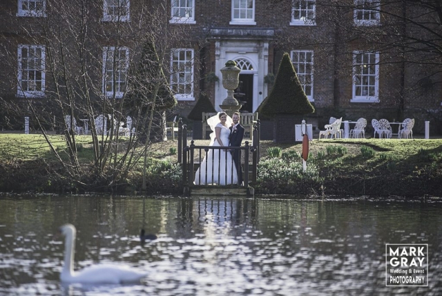 Bride and groom from across the lake at Chilston Park Hotel