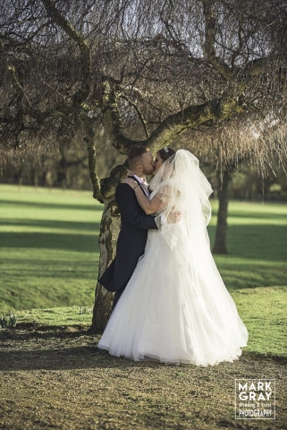 Bride and groom enjoy a kiss in the grounds at Chilston Park Hotel