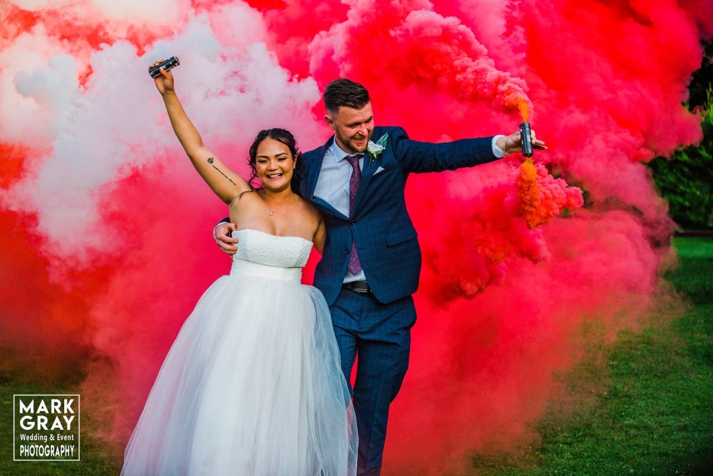 Bride and groom with red and white smoke bombs